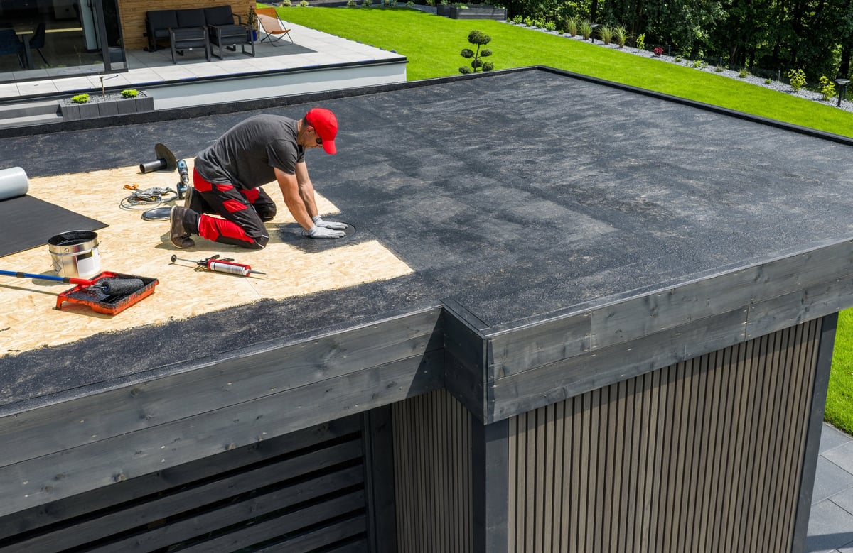 Worker applying roofing membrane to a flat roof